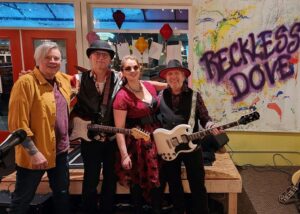 4 person band in front of reckless dove banner