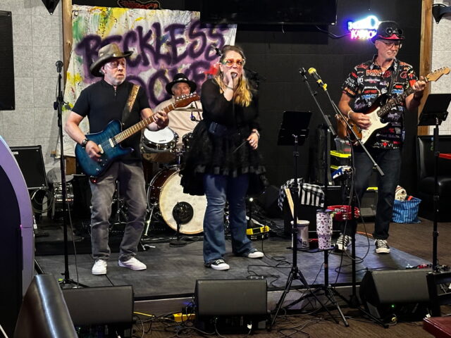 4 person rock band in front of banner Reckless Dove
